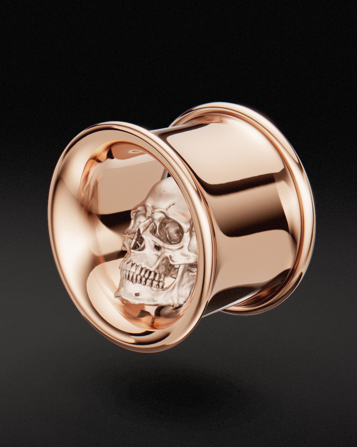 Rose gold ear tunnels with skull design on dark background